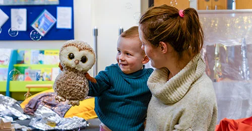 Mother and child smiling holding an soft owl toy