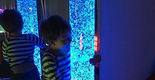 Child hugs a blue bubbled sensory light