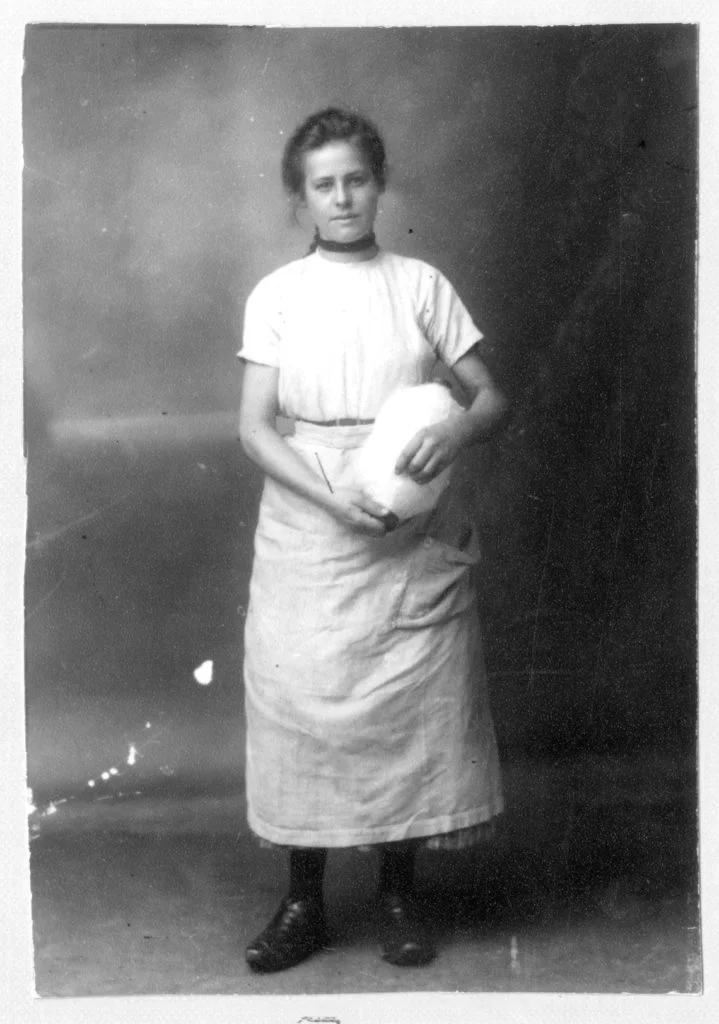 Photograph of a woman mill worker holding a full spool of cotton.
Image reference: P47054