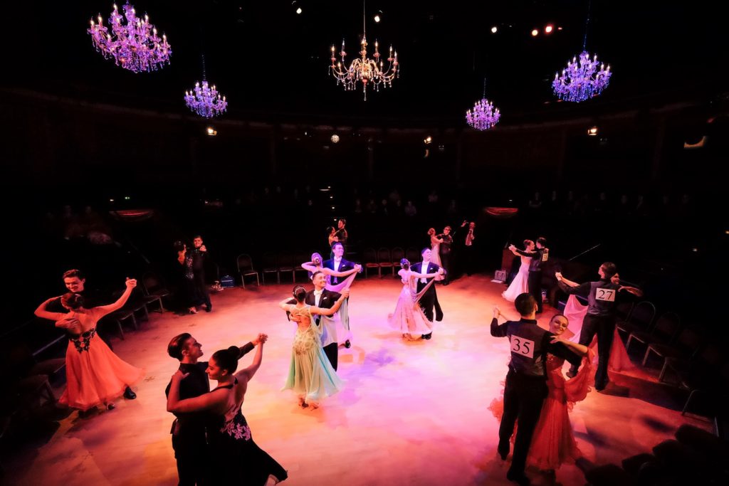 Numerous couples ballroom dancing on the stage.
