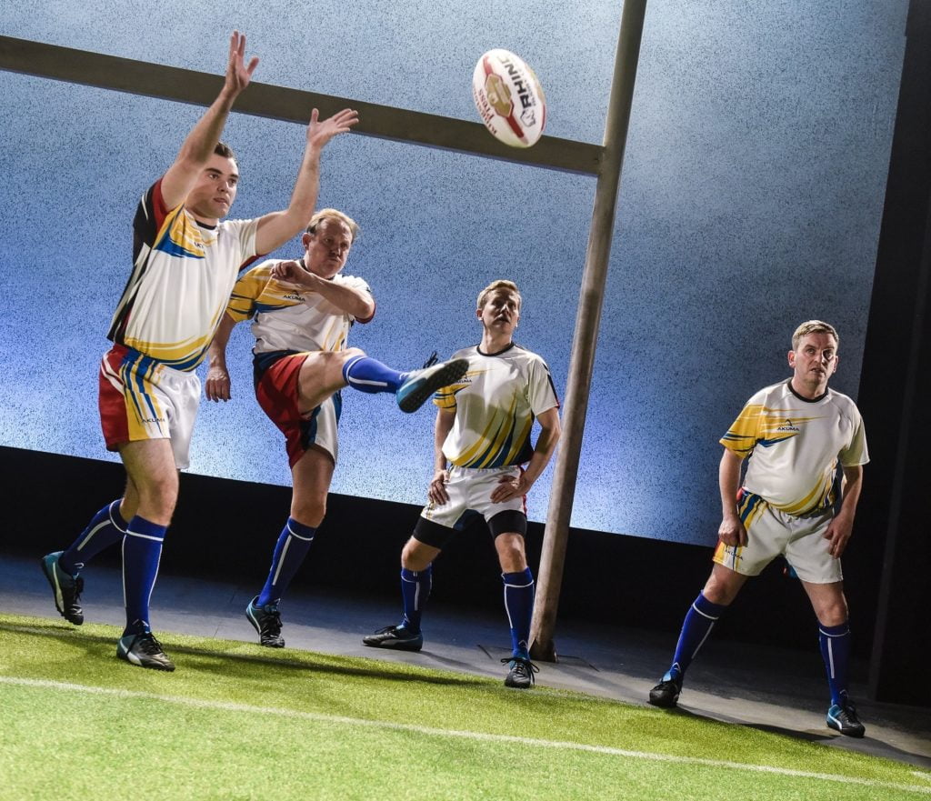 Four men in Rugby shirts throwing a rugby ball.